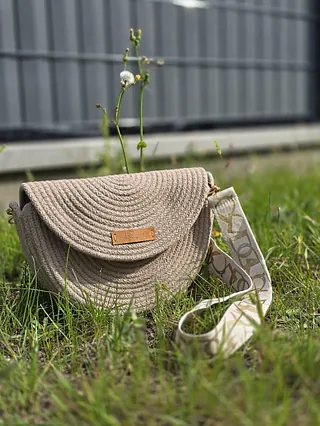 Ein geflochtener Korb, gefüllt mit verschiedenen Wollknäueln und einer Häkelnadel.